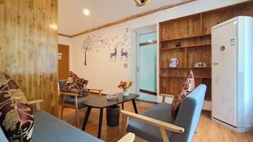 Un salon confortable avec un canapé, des fauteuils, une petite table et une bibliothèque.