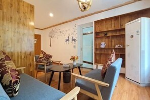 A cozy living room with a sofa, armchairs, a small table, and a bookshelf. - Zhangjiajie YiShang Inn (Zhangjiajie)