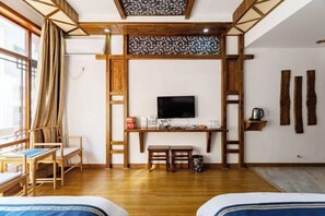 Ein Zimmer mit einem Holztisch, einem Fernseher und einem Bett.