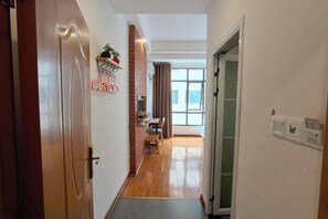 A hallway with a wooden floor, a brick wall, and a window with curtains. - Zhangjiajie YiShang Inn (Zhangjiajie)