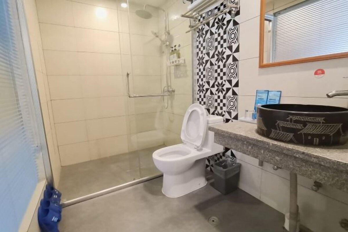 A bathroom with a white toilet, a shower area, and a sink with a patterned backsplash.