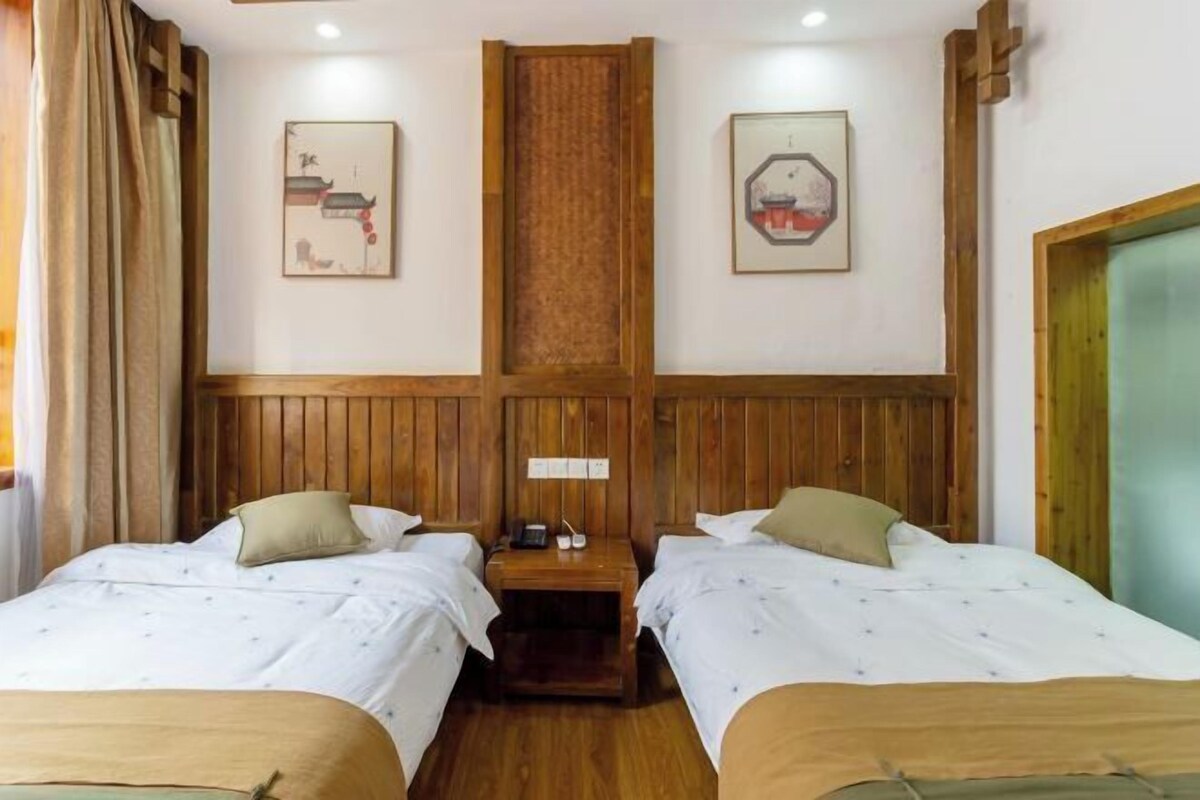A hotel room with two beds, wooden paneling, and artwork on the walls.