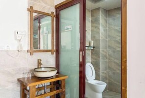 A bathroom with a wooden vanity, a bowl sink, a toilet, and a glass shower enclosure. - Zhangjiajie YiShang Inn (Zhangjiajie)