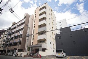 A multi-story residential building with balconies, a gated entrance, and a parked van. - Daikoku Apartment 601 - Namba Apt3 minJR Imamiya/Daikokucho St/Veranda (Osaka)