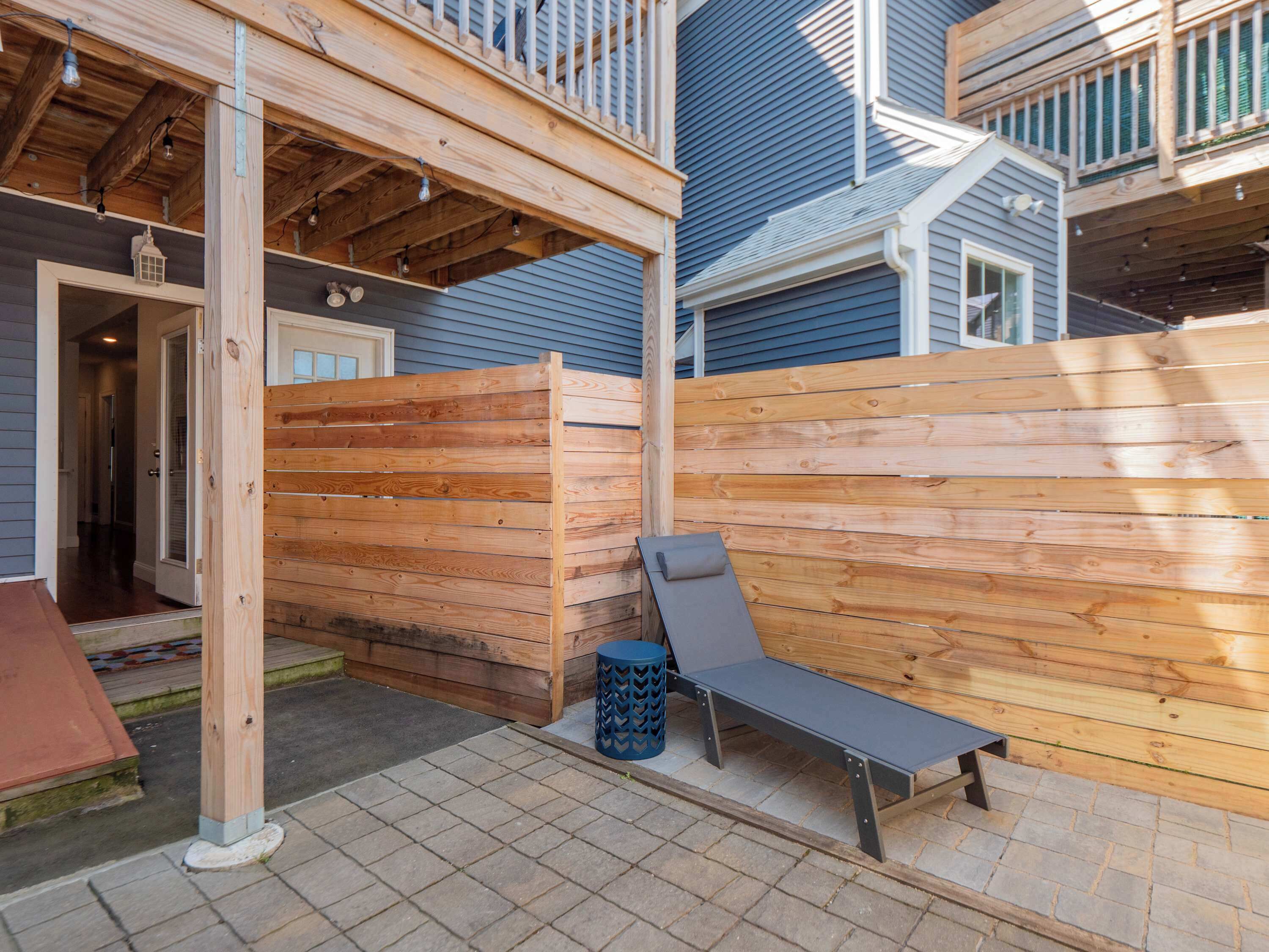 Une terrasse en bois avec un banc en métal et une lanterne.