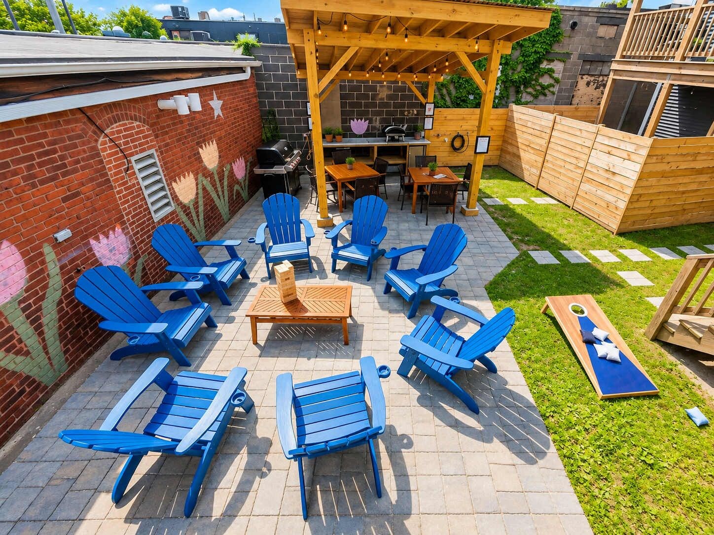 Un espace patio aménagé avec des chaises Adirondack bleues, une table en bois et un barbecue.