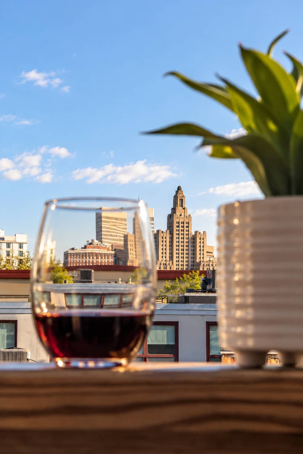 A glass of red wine on a table with a city skyline in the background.