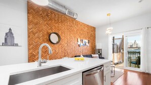 Een moderne keuken met een wand van visgraat hout, roestvrijstalen apparatuur en uitzicht op de stad door de glazen deur.