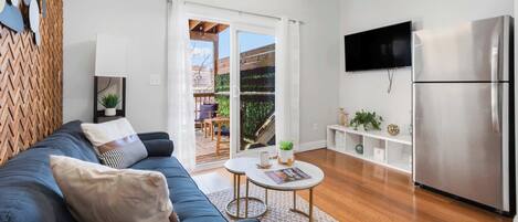 A modern living room with a sofa, a coffee table, a TV, and a kitchen area with a refrigerator.