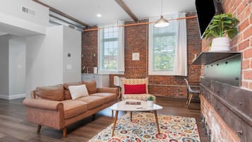 Una sala de estar moderna con un sofá de cuero marrón, una mesa de centro blanca y un tapete floral colorido.