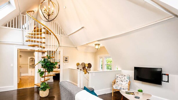Een ruime loft met een houten trap, een flatscreen televisie en een gezellige zithoek.