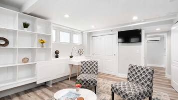 A modern living room with white furniture, a round coffee table, and patterned chairs.