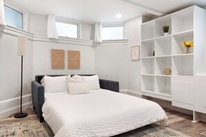 Une chambre à coucher comprenant un lit, une lampe de sol, une bibliothèque et deux panneaux décoratifs fixés au mur.