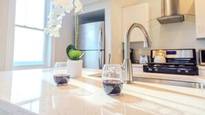 A modern kitchen with a stainless steel faucet, a wine glass, and a potted orchid on the counter.