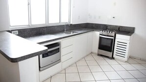 A kitchen with white cabinets, a dishwasher, a stove, and a sink.