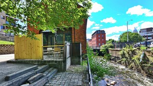 A building with a brick facade, a wooden fence, and a stone staircase leading to a door. - Jennifer’s Historic Riverfront Loft Private Entry (Providence)