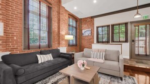A room with a brick wall, two sofas, a coffee table, and an exit sign. - Jennifer’s Historic Riverfront Loft Private Entry (Providence)
