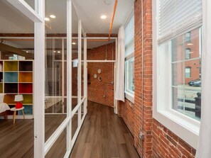 An interior with a brick wall, a window, and a glass partition. - Jennifer’s Historic Loft | Glass-Enclosed Bedroom (Providence)