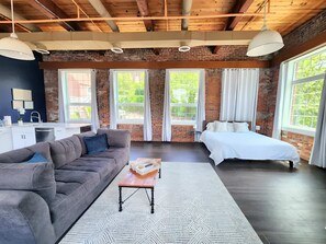 Une chambre moderne comprenant un canapé, un lit, une petite table et un coin cuisine.