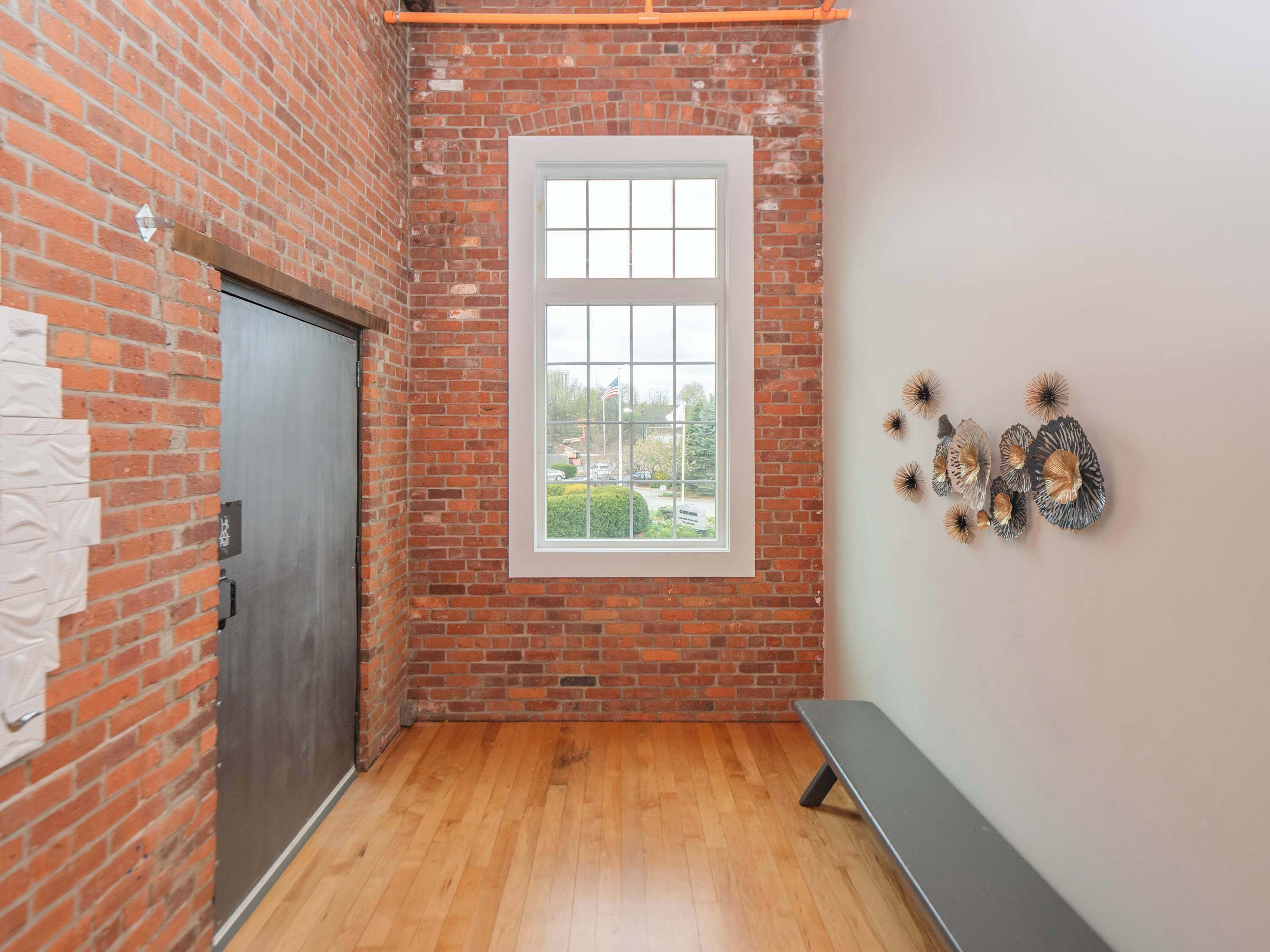 Ein Zimmer mit Backsteinwand, einem Fenster, einer Bank und Wanddekoration.