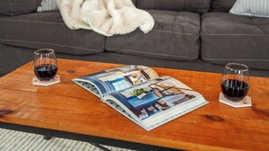 A living room with a sofa, two glasses of red wine, and a magazine on a coffee table. - Jennifer’s Historic Penthouse Loft | City Views (Providence)