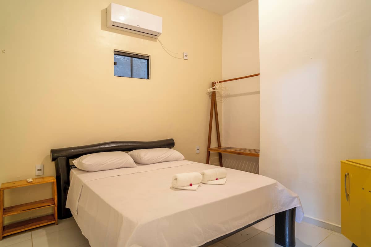 Une chambre à coucher comprenant un lit, une table de chevet, une armoire et un appareil de climatisation.