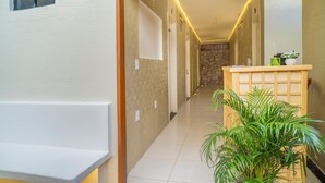 A hallway with a wooden bench, a potted plant, and a reception desk. - Pe na Areia Pousada Jeri (Jijoca de Jericoacoara)