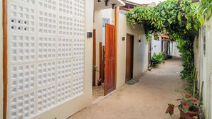 A narrow alleyway with a wooden gate, a white lattice fence, and potted plants. - Pe na Areia Pousada Jeri (Jijoca de Jericoacoara)