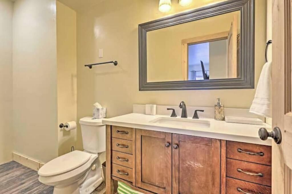 Une salle de bain équipée de toilettes, d’un lavabo, d’un miroir et d’un meuble en bois.