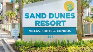 Een bordje voor Sand Dunes Resort met de tekst dat het villa's, suites en appartementen aanbiedt.