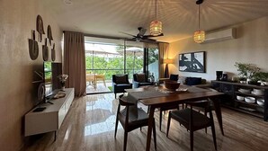 A spacious living area with a dining table, chairs, a sofa, and a ceiling fan. - AWA Playacar 2BR - Resort Pools, Balcony, Walk to Beach (Playa del Carmen)