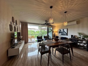 A spacious living area with a dining table, chairs, a sofa, and a ceiling fan.