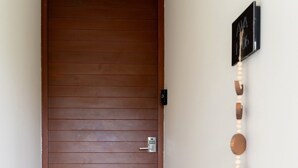 A wooden door with a keypad lock, a wall-mounted picture, and a decorative wooden wall hanging. - AWA Playacar 2BR - Resort Pools, Balcony, Walk to Beach (Playa del Carmen)