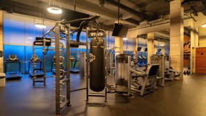 A gym with various exercise equipment, including a squat rack, a punching bag, and cardio machines. - AWA Playacar 2BR - Resort Pools, Balcony, Walk to Beach (Playa del Carmen)
