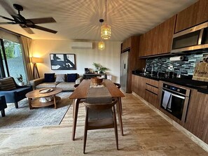Een moderne keuken met houten kastjes, een inbouwoven en een eethoek met een houten tafel en stoelen.