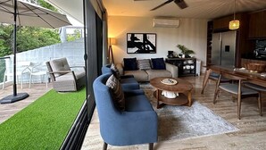 A modern living room with a sofa set, a coffee table, and a dining area with chairs. - AWA Playacar 2BR - Resort Pools, Balcony, Walk to Beach (Playa del Carmen)