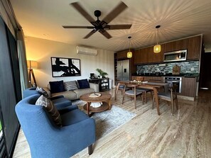 Een moderne woonkamer met een bank, salontafel en eethoek.