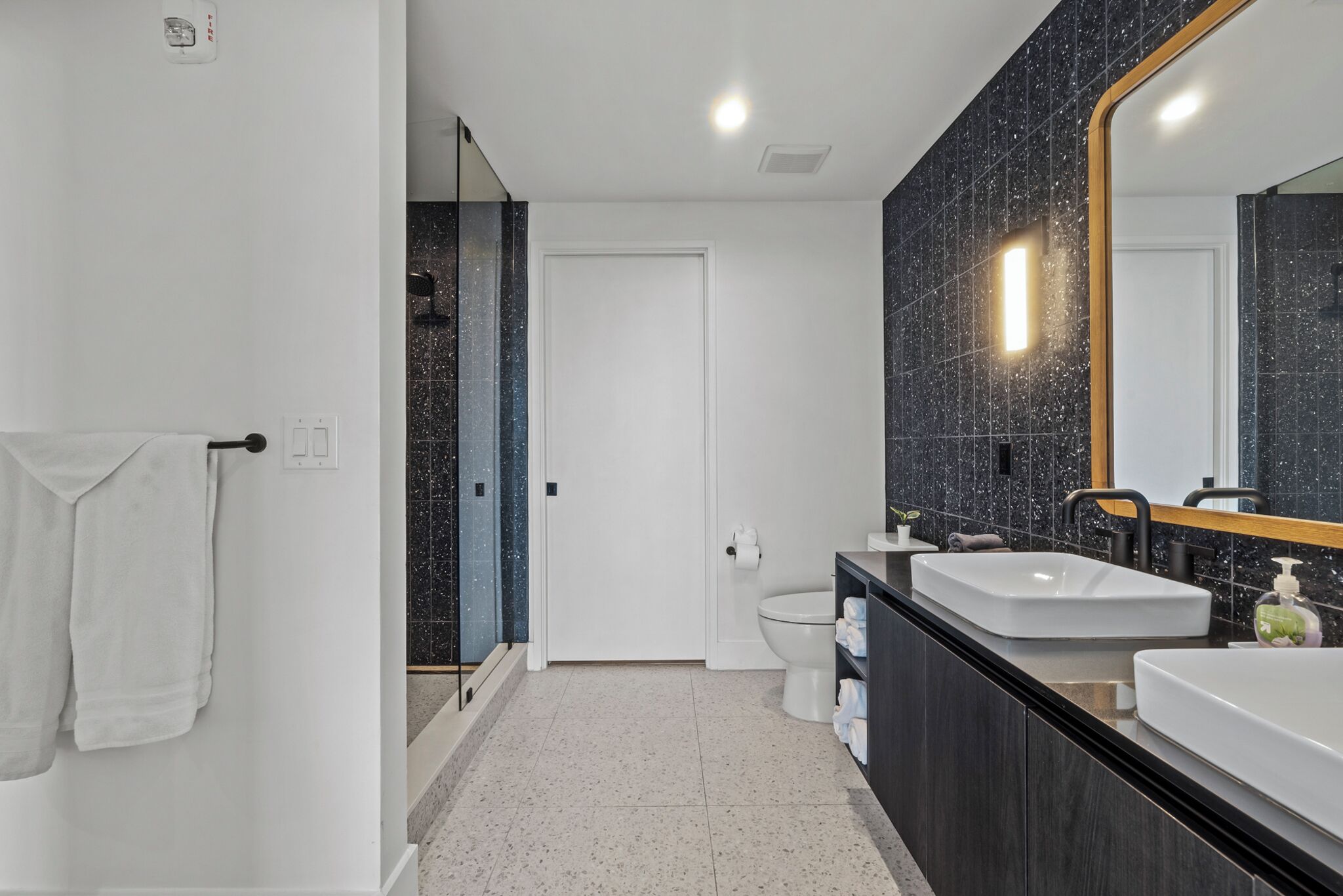Een moderne badkamer met een grote spiegel, twee wasbakken en een toilet.