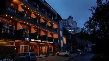 A multi-story hotel with balconies and a sign for 'Clovis Hotel & Family Restaurant'.