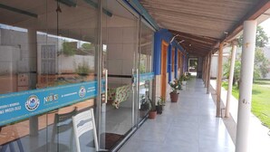 A covered corridor with glass doors, potted plants, and a tiled floor. - Pousada Estância da Mata (Nobres)
