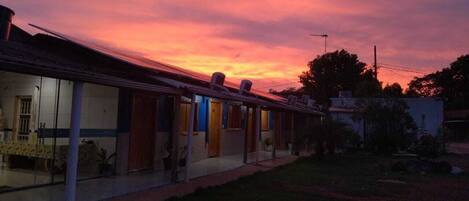 A row of single-story buildings with a flat roof, likely a motel or small hotel, with a clear sky in the background.