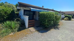 Un petit bâtiment avec un toit en tuiles, une grande fenêtre et une allée gravillonnée.