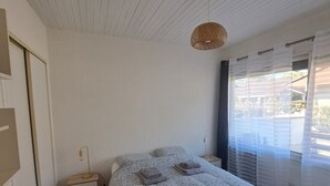 Une chambre à coucher avec un lit, une table de chevet, une lampe et une fenêtre avec des rideaux.