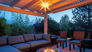 An outdoor patio with a fire pit, a sofa, and wicker chairs.