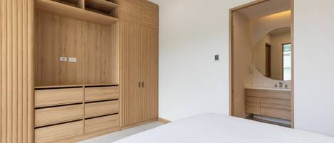 A bedroom with a large wardrobe, a bed, and a bathroom with a mirror and sink.