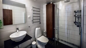 Une salle de bain moderne avec un grand miroir, un lavabo, des toilettes et une douche à parois de verre.