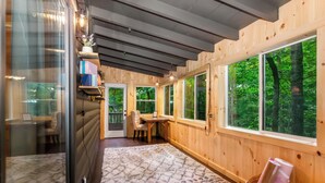 Ein gemütliches Blockhäuschen im Inneren mit Holzwänden, großen Fenstern, einem Schreibtisch und einem Sessel.