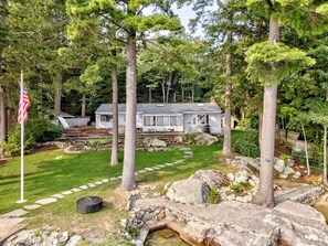A house surrounded by trees, with a stone pathway leading to the front door.