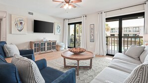 Ein Wohnzimmer mit Deckenventilator, Flachbildfernseher, rundem Couchtisch und einer Couch.