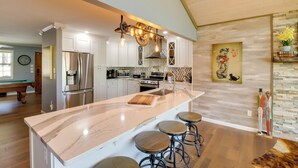 A modern kitchen with a large island, stainless steel appliances, and a unique ceiling light fixture. - Lakeside Retreat on 10 Secluded Wooded Acres, Hot Tub, Level 2 EV Charger (Greers Ferry)